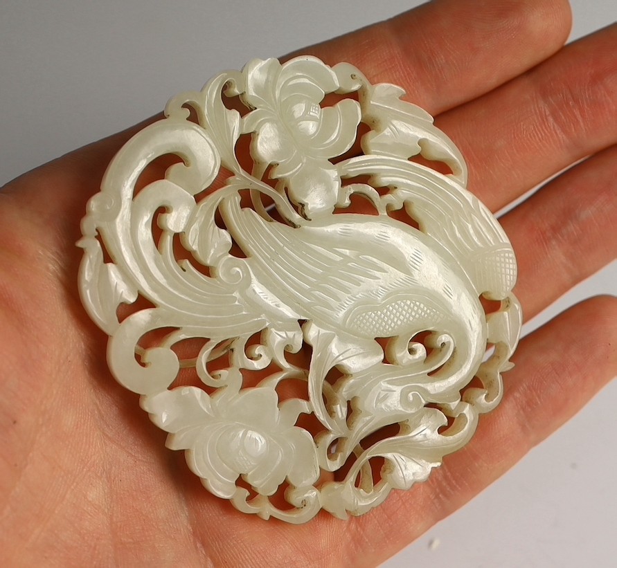 A Chinese white jade ‘phoenix and peony’ reticulated plaque, early 19th century, 6.9cm wide, wood stand